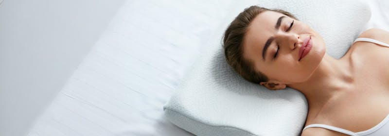 woman lays her head comfortably on pillow in a med spa or aesthetic surgery center setting