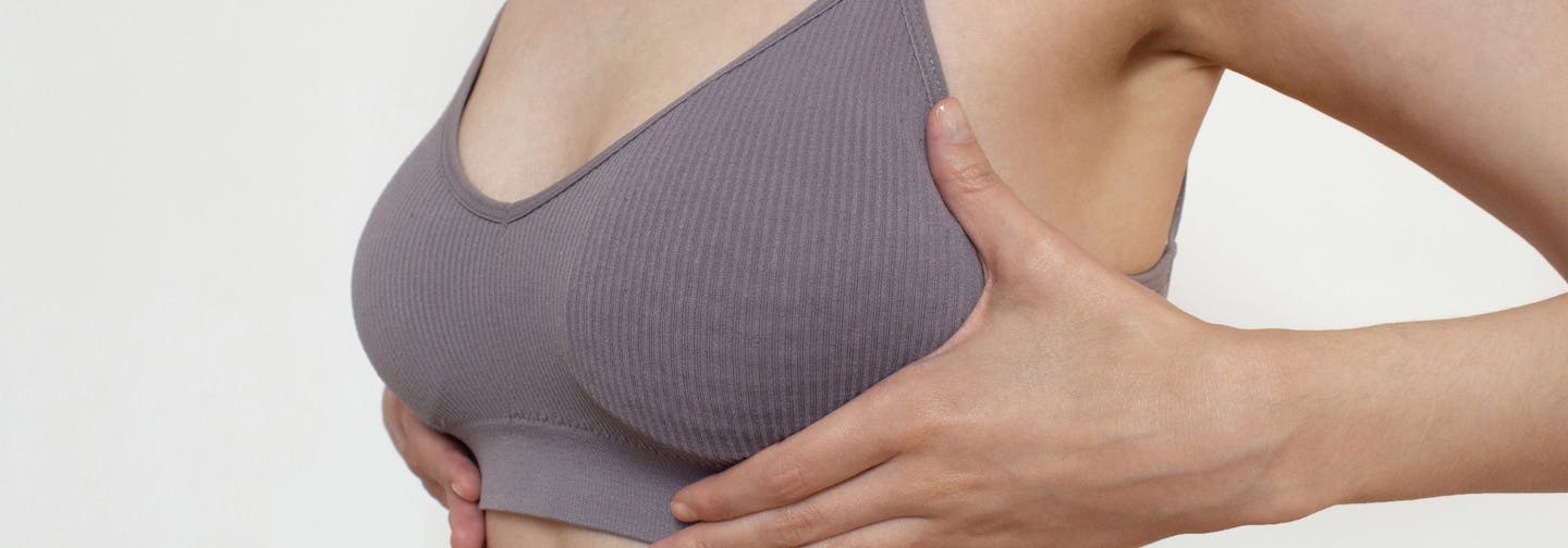 woman with hands below bra sizes up her chest