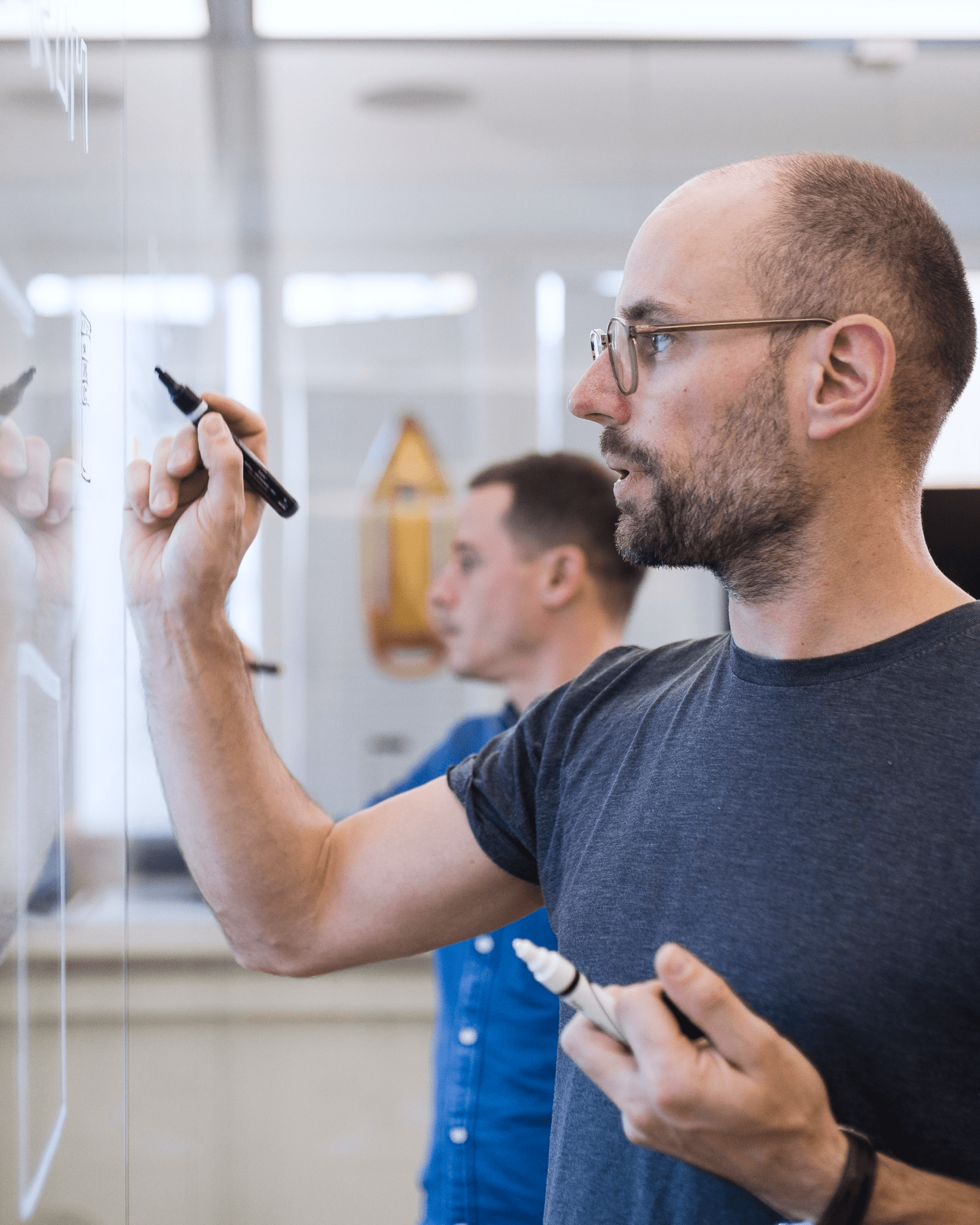 Two dreipol employees writing on a glass wall with markers.