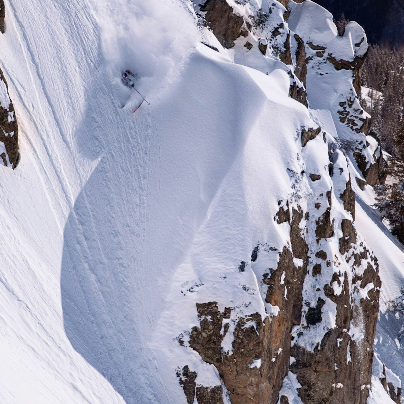 A skier skiing down a steep mountain slope.