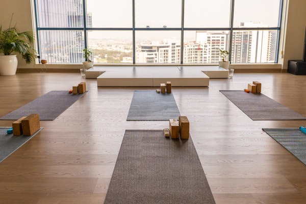 A tranquil yoga studio with mats, blocks, and a panoramic cityscape view through large windows, offering a calm and peaceful atmosphere for meditation and yoga practice