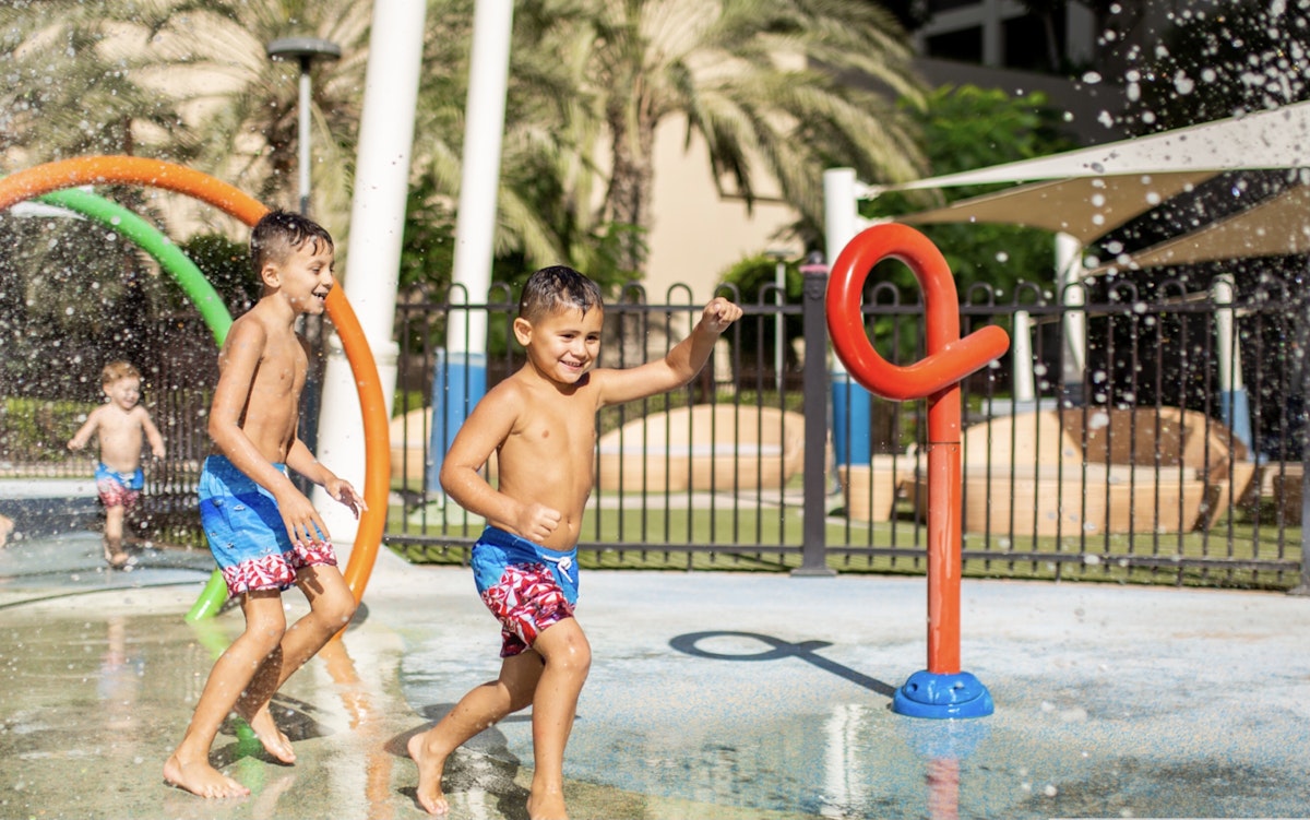 Children playing in a water park with colorful spray features.