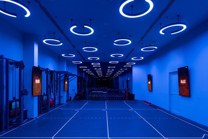 Modern gym interior with blue lighting and exercise equipment.