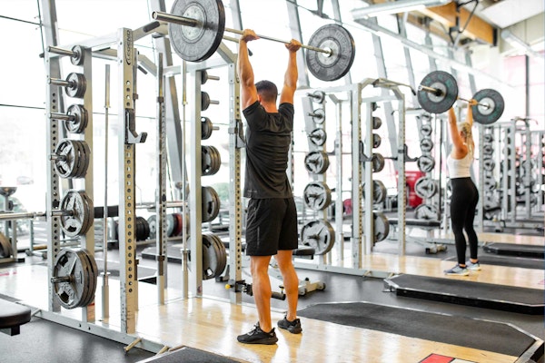 A man and a woman lifting weights in a gym.