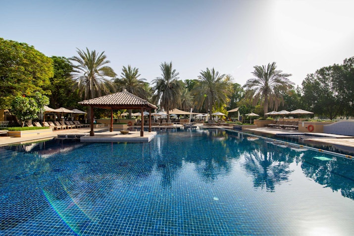 A serene poolside area surrounded by palm trees and wooden cabanas