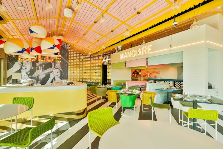 A colorful and lively restaurant interior featuring green chairs, striped floors, and a modern Italian theme.