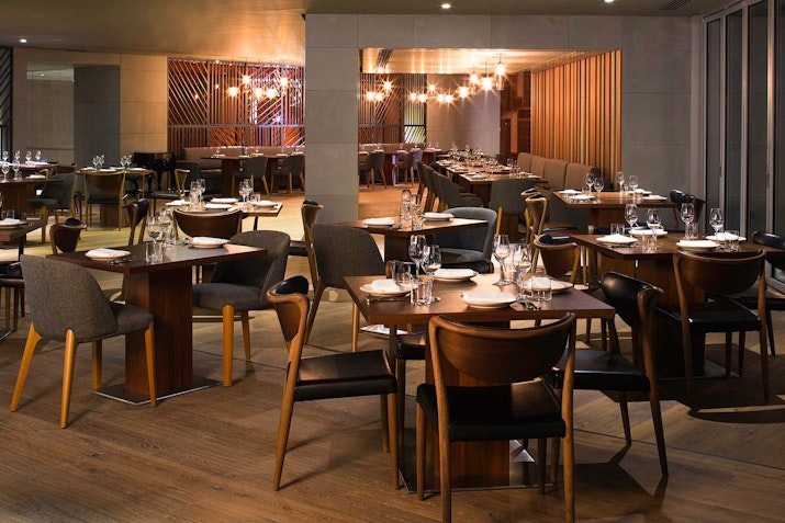 A sophisticated restaurant interior featuring dark wood tables, ambient lighting.