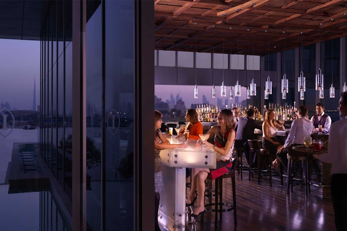 Vista Restaurant & Terrace, InterContinental Festival City People enjoying drinks at a stylish rooftop bar with city skyline views in the evening