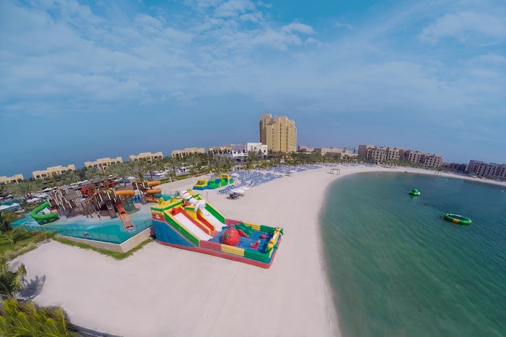 Aerial view of a beach with a colorful water park and sandy shoreline.