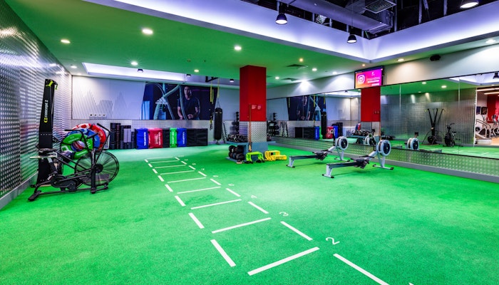 Fitness First Functional training area with green turf, workout equipment, and mirrored walls.
