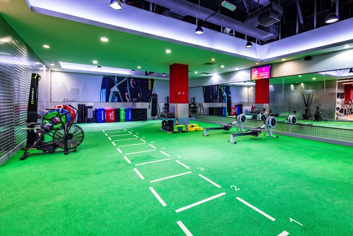 Functional training area with green turf, workout equipment, and mirrored walls.