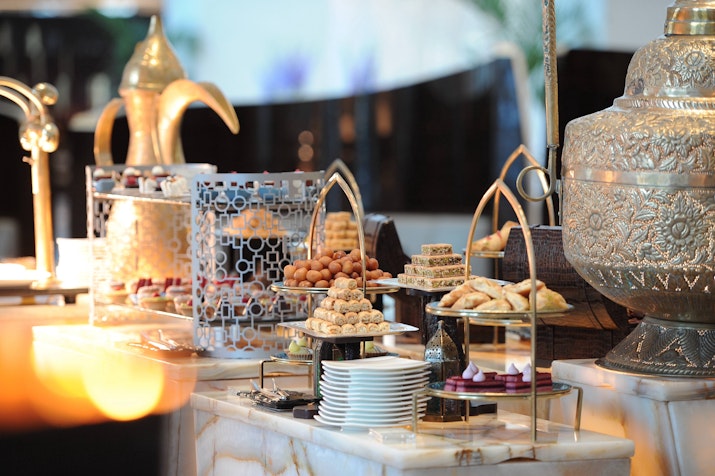 A luxurious display of assorted pastries and sweets on an elegantly arranged dessert table, featuring intricate serving trays and traditional décor elements.