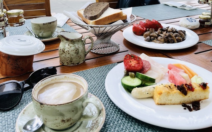 A well-balanced breakfast spread featuring fresh vegetables, fruits, mushrooms, bread, and coffee.