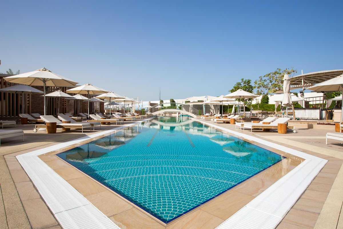 A luxurious outdoor pool surrounded by sun loungers and umbrellas, offering a relaxing atmosphere.
