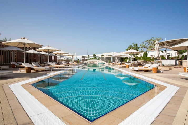 A luxurious outdoor pool surrounded by sun loungers and umbrellas, offering a relaxing atmosphere.