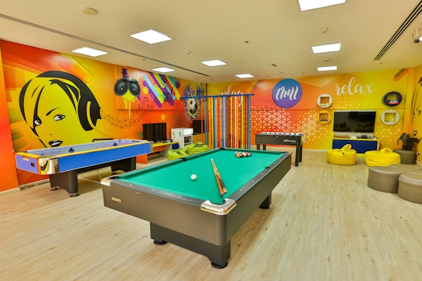 Anantara The Palm Dubai Resort A vibrant game room featuring a pool table, air hockey table, colorful walls, and cozy seating.
