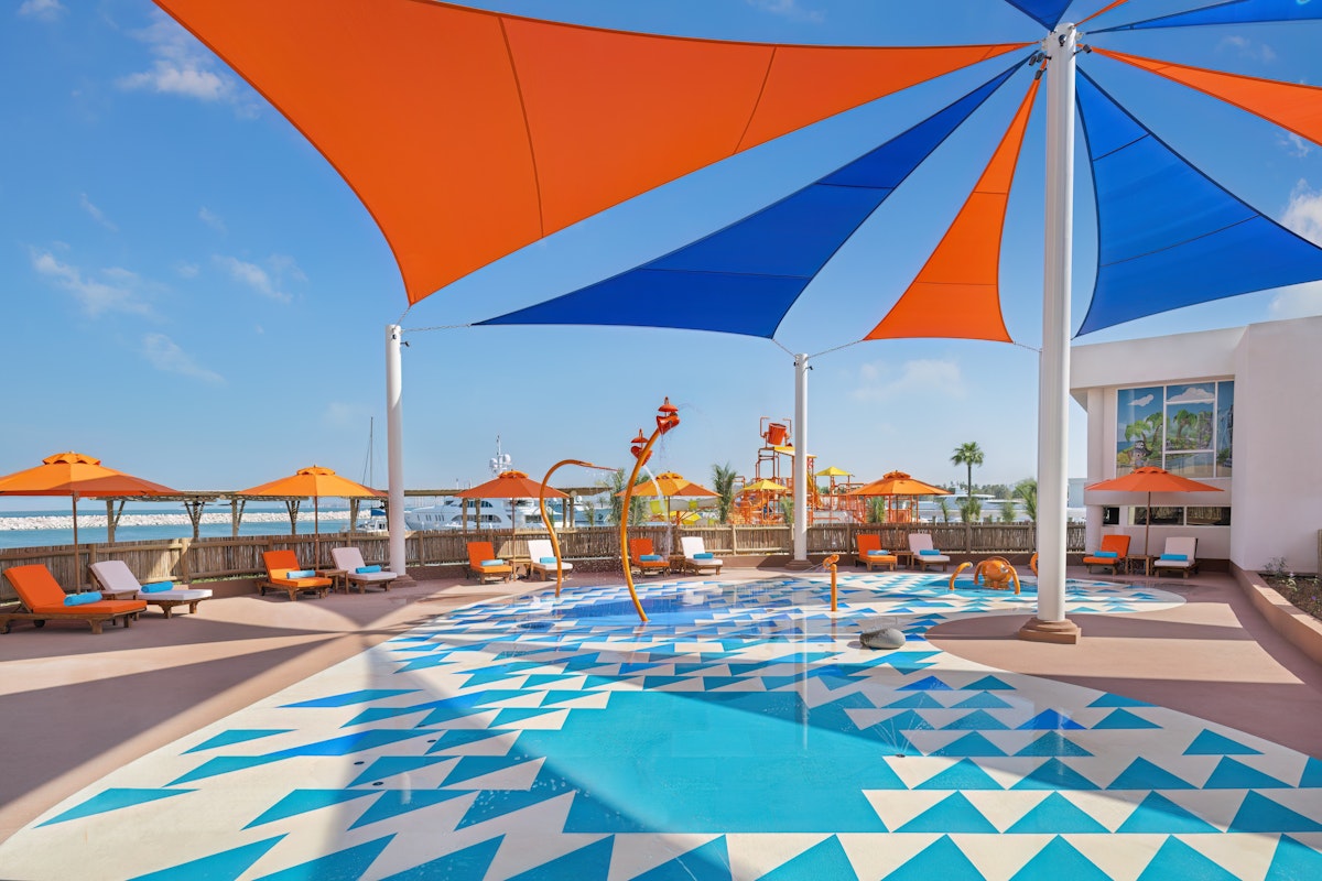 Colorful splash pad with shaded canopies and seating area.
