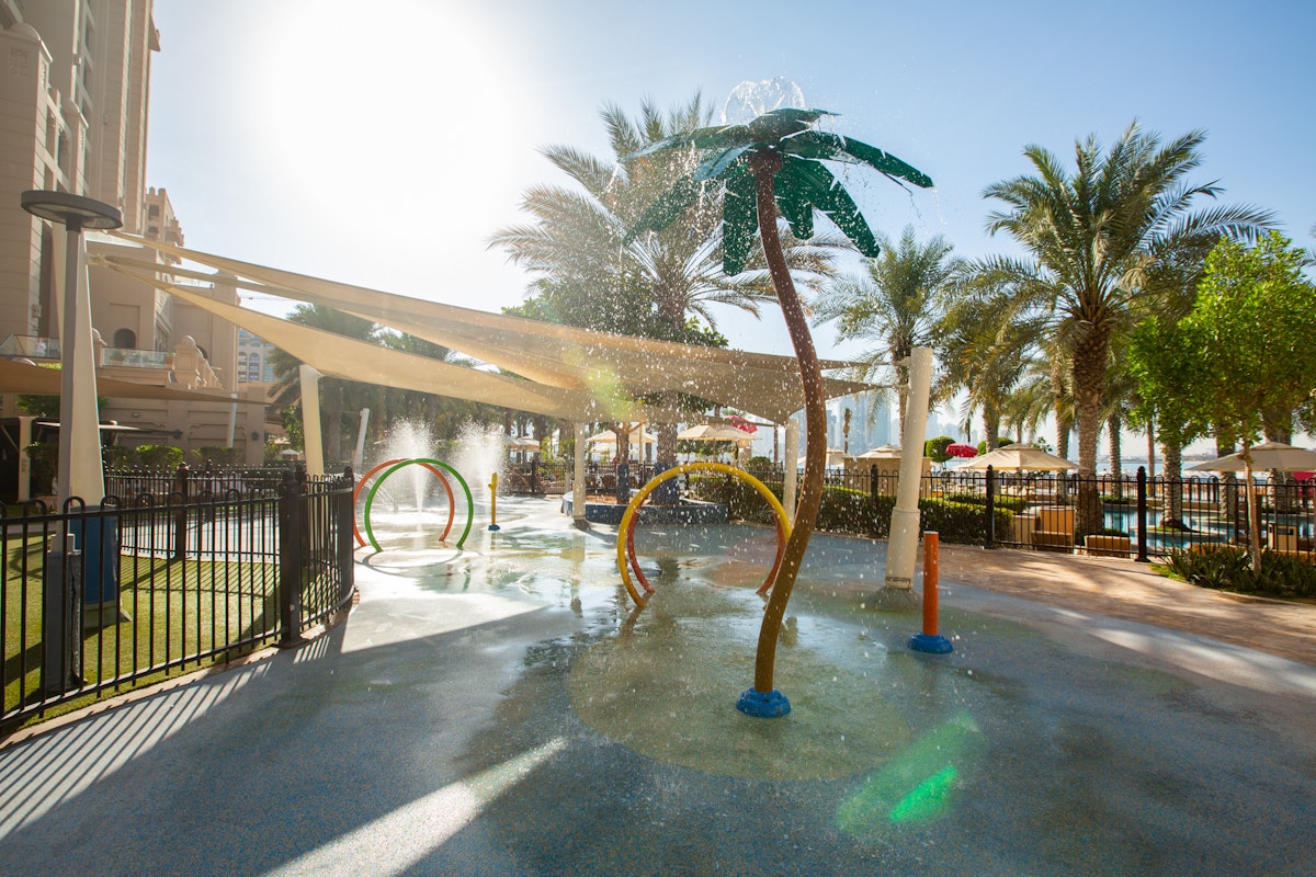 Water playground with colorful water jets and palm tree-shaped sprayers.