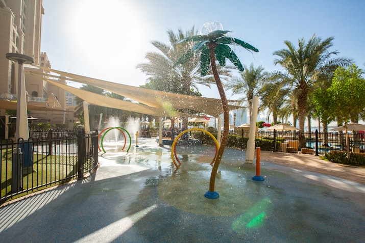 Water playground with colorful water jets and palm tree-shaped sprayers.