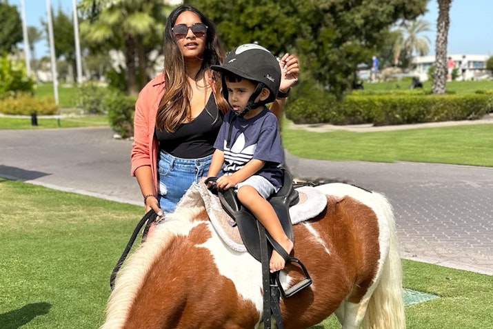 A woman and child riding a pony.