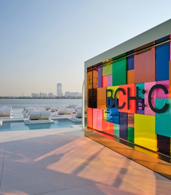 BCH:CLB Colorful glass wall overlooking lounge chairs and water views.