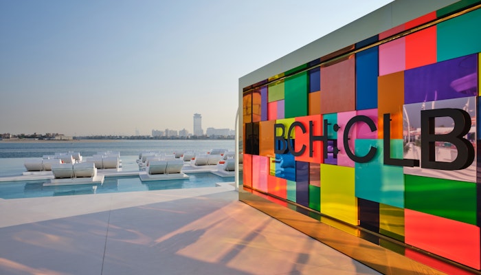 BCH:CLB Colorful glass wall overlooking lounge chairs and water views.