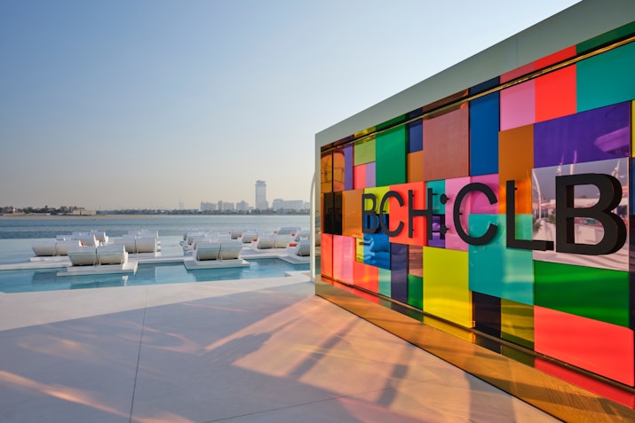 Colorful glass wall overlooking lounge chairs and water views.