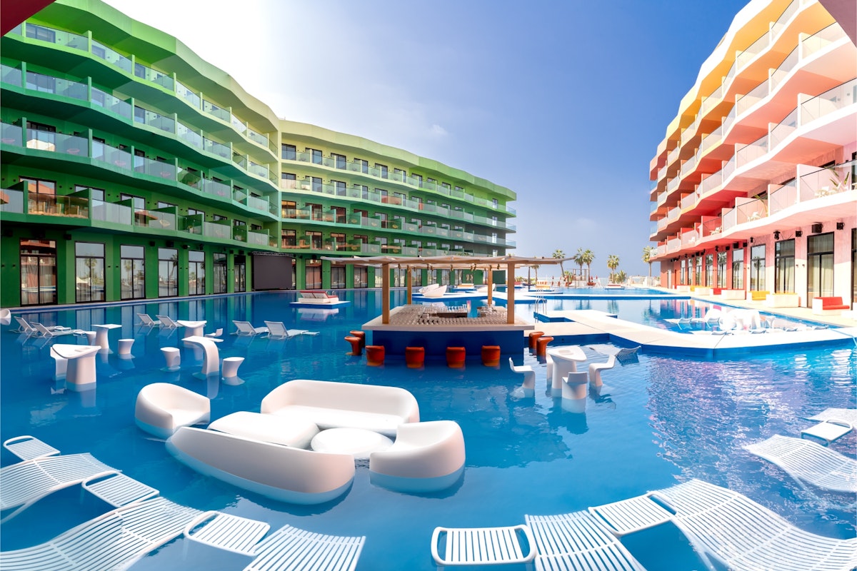 Colorful resort buildings surrounding a pool with in-water lounge seating
