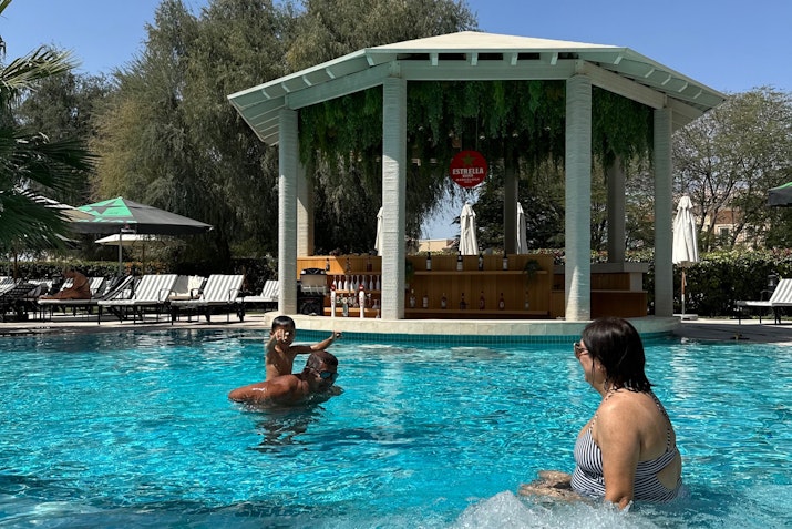A family enjoying the pool with a poolside bar in the background.
