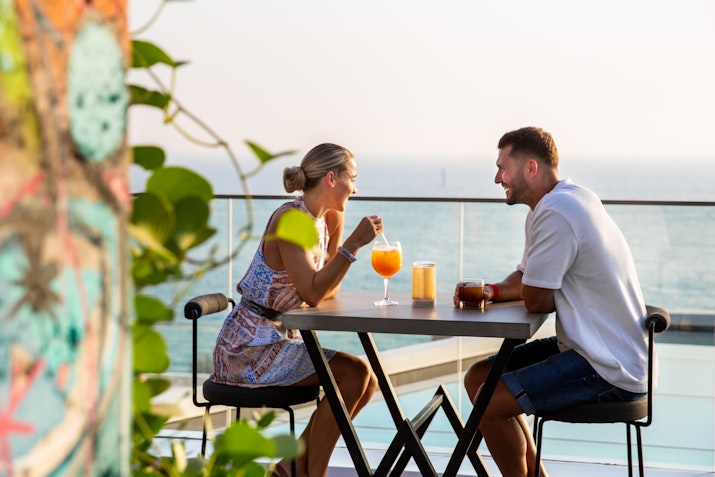 A couple enjoying drinks at a table with a view of the sea.