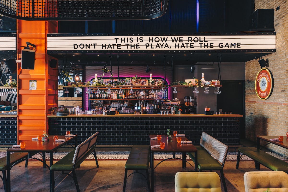 Enjoy bowling, burgers, arcade games, and more fun at Central Abu Dhabi! Bar with industrial elements like metal and brick with playful decor elements that create a lively, social ambiance.