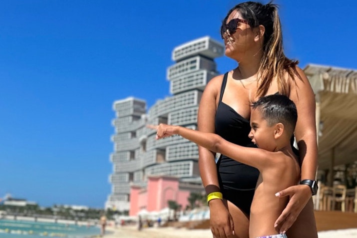 A woman and child at the beach, with the child pointing at something in the distance.