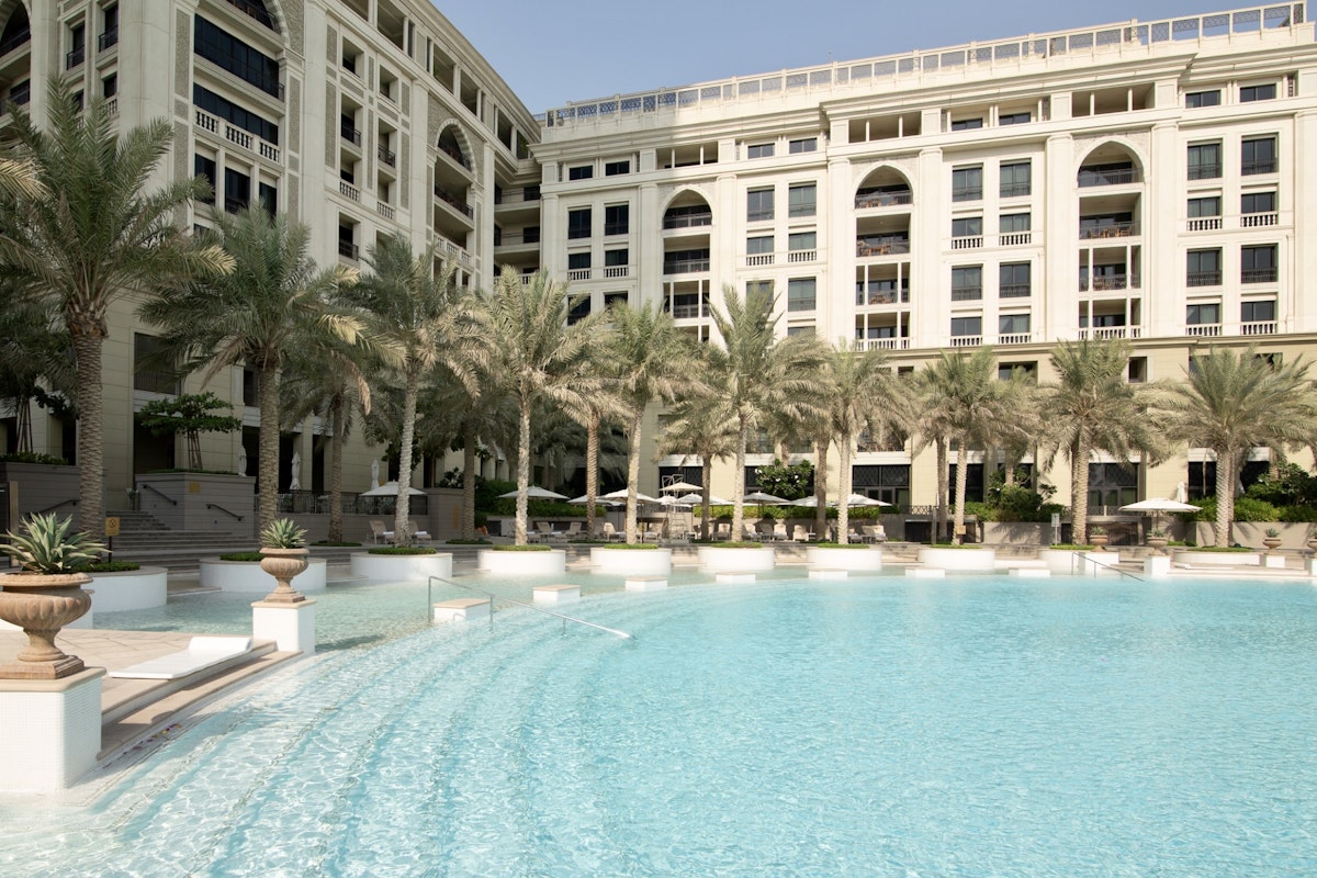 Creekside Privilee spots A luxurious swimming pool with gentle slopes, surrounded by palm trees and elegant resort architecture.