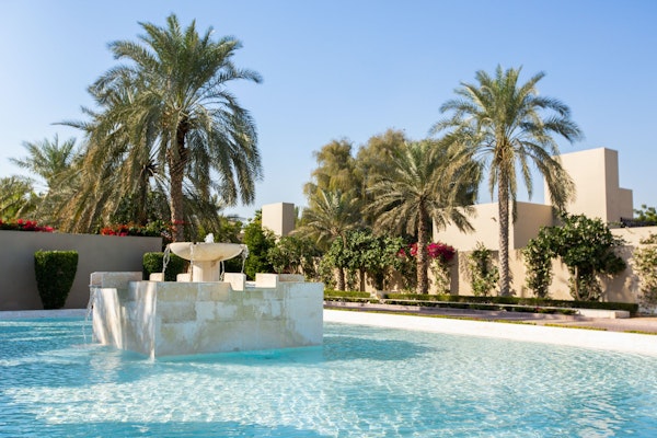 Fountain in a pool surrounded by palm trees and greenery