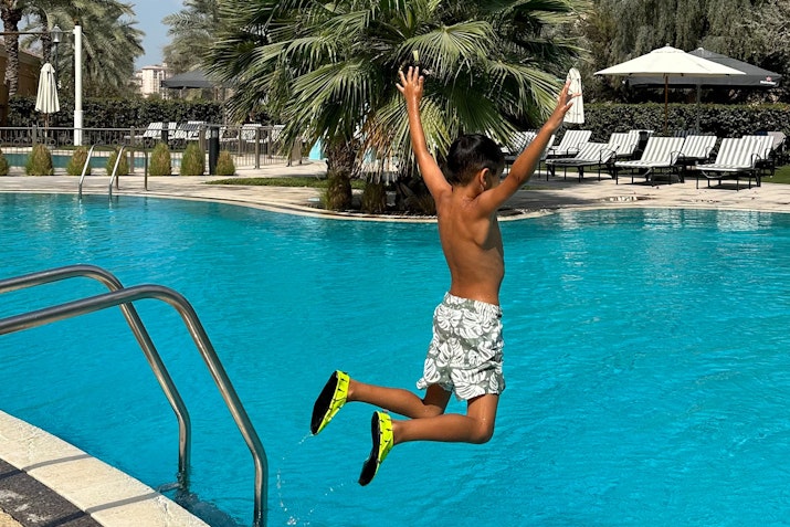A child jumping into a pool from the side.
