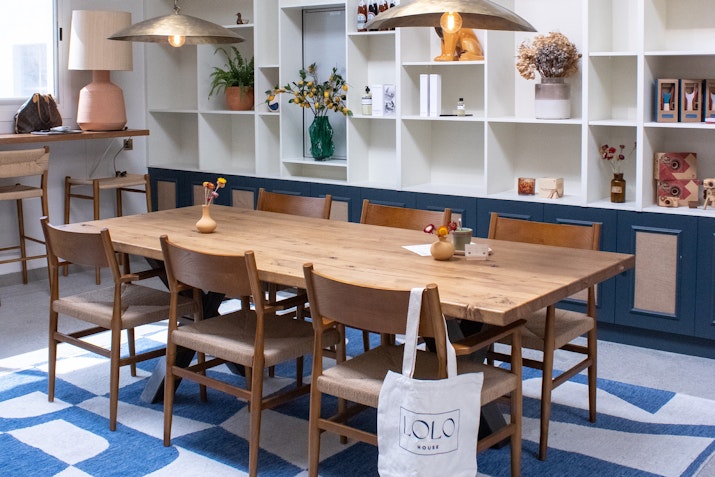 Cozy dining area with wooden table, chairs, and decorative shelving in the background.