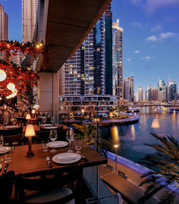Papas at InterContinental Dubai Marina Open air restaurant with ambiant lighting and wooden dining tables overlooking the water
