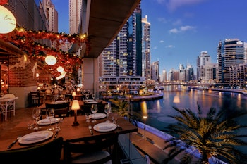 Open air restaurant with ambiant lighting and wooden dining tables overlooking the water