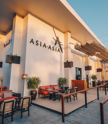 Asia Asia, Yas Bay Outdoor seating area at Asia Asia restaurant with red chairs and tables.
