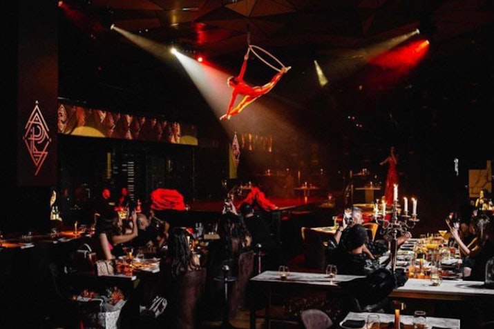 PLAY Restaurant & Lounge Dimly lit restaurant with aerial acrobat performance above diners, creating a dramatic ambiance.