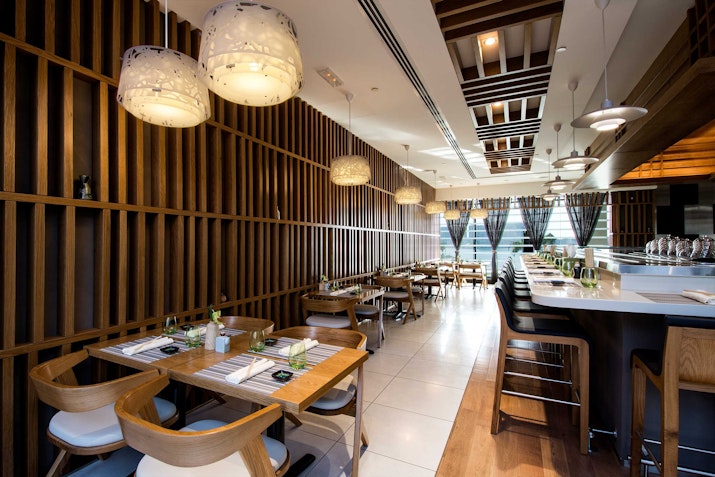 Contemporary restaurant interior with stylish lighting, wooden accents, and neatly set tables.
