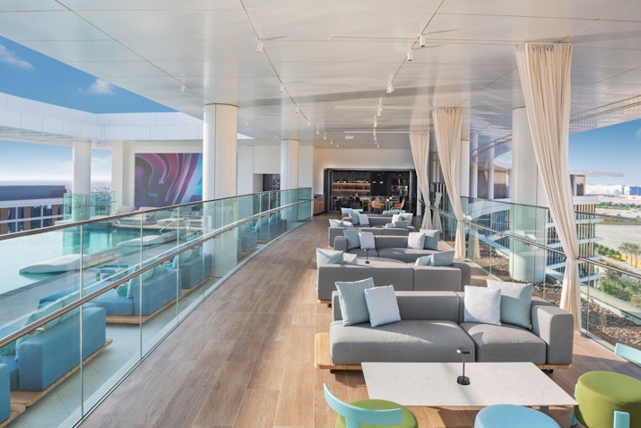 The WB Abu Dhabi Modern lounge area with stylish sofas and colorful chairs, offering panoramic views through large windows.