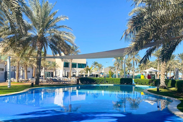 Swimming pool with palm trees and shaded lounge areas