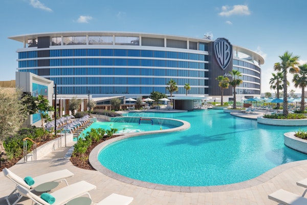 Poolside view of Warner Bros. hotel with sun loungers and palm trees