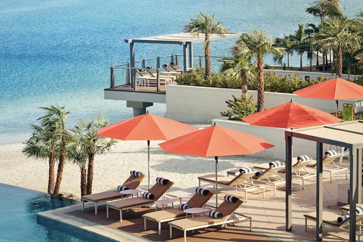 Beach lounge chairs with umbrellas and a view of the water.