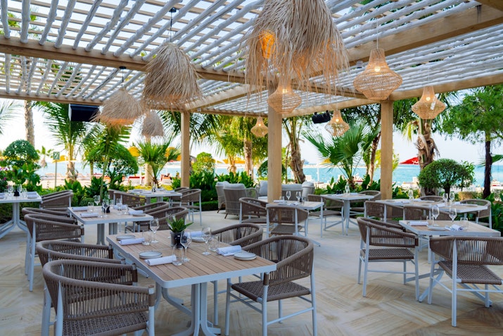 Beachside outdoor restaurant with wicker decor and ocean view
