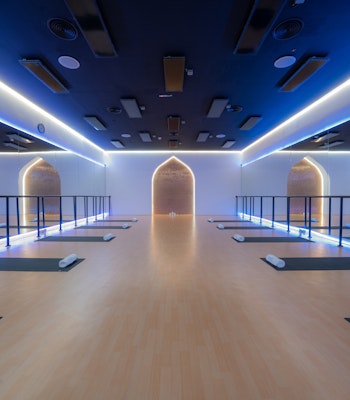 TruFusion Dubai Yoga Studio Modern yoga studio with soft lighting, wooden flooring, yoga mats, and mirrored walls.