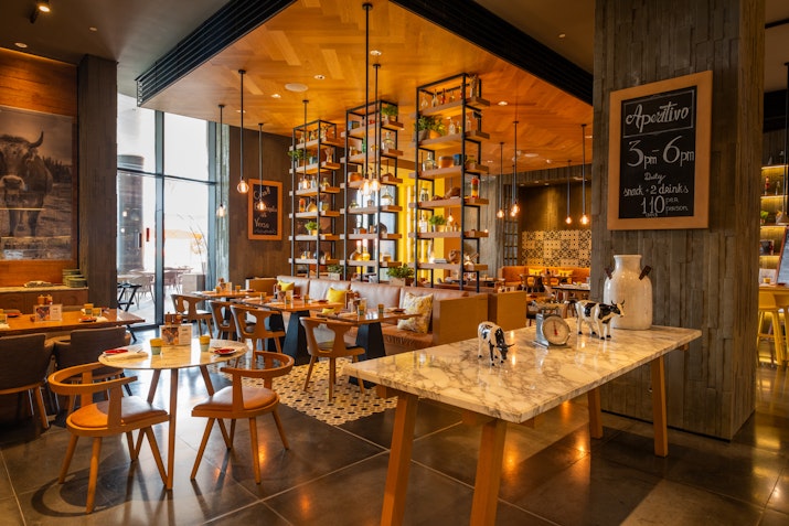 Interior of a warm, stylish dining area with modern decor and marble tables.