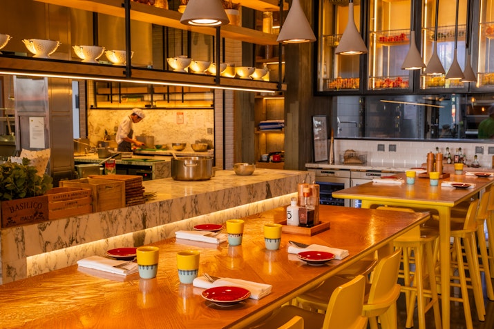 Interior view of a cozy, modern dining area with open kitchen and vibrant decor.