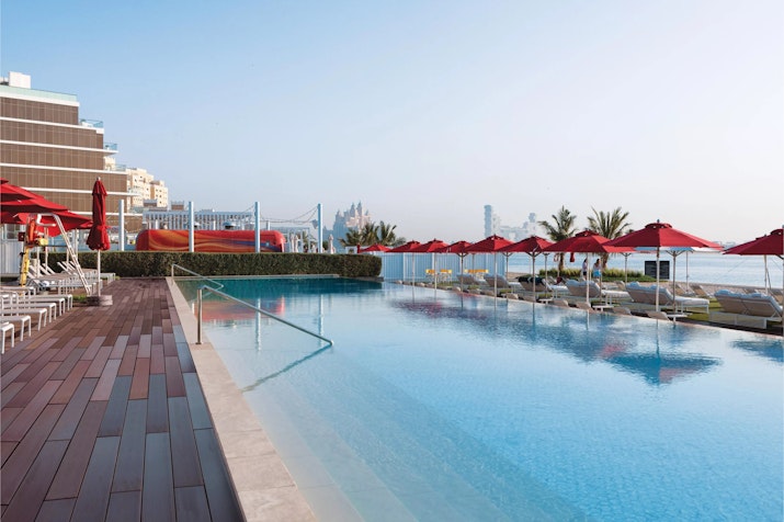 Infinity pool with red umbrellas and ocean views.